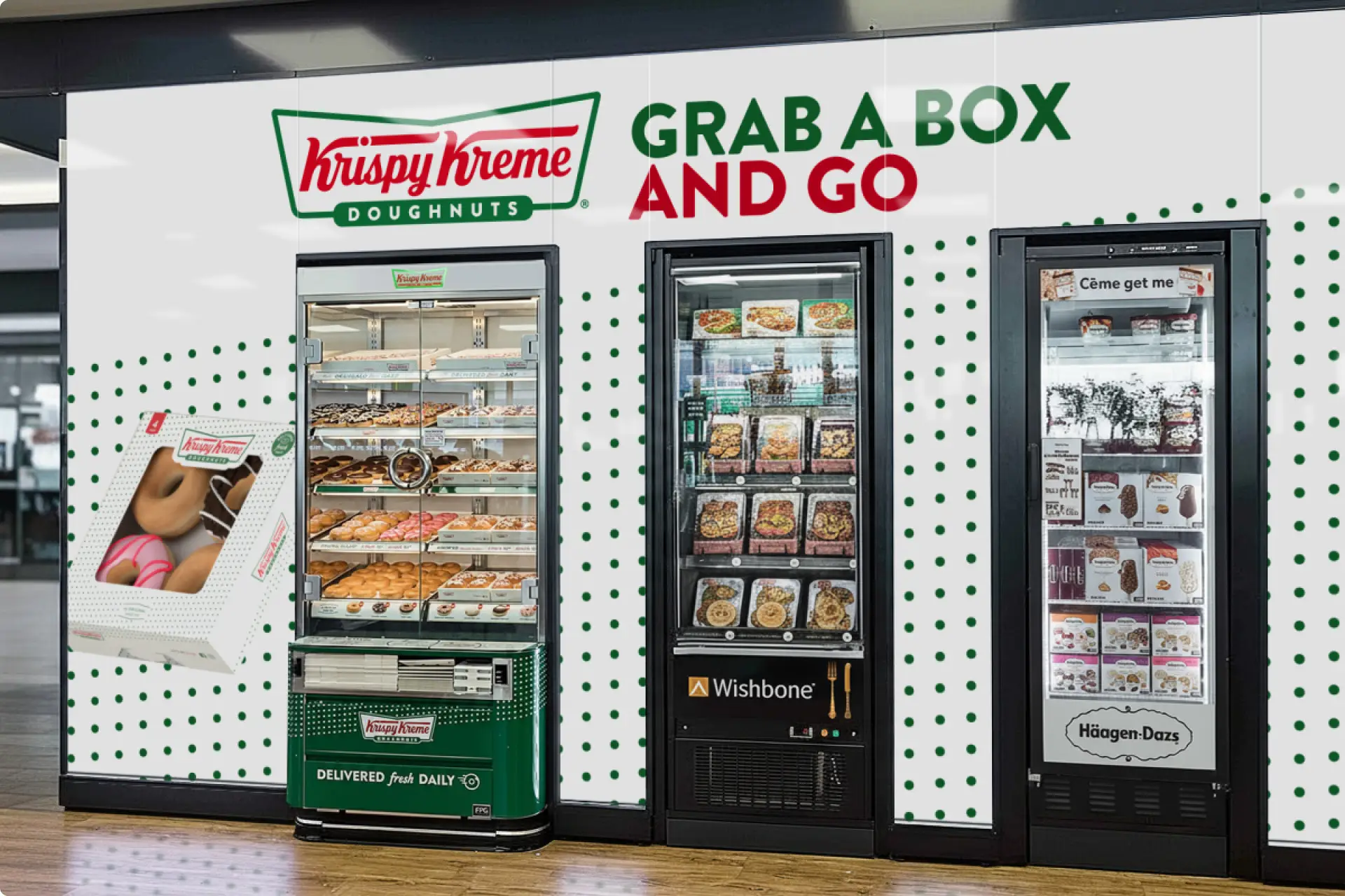 A branded Krispy Kreme grab-and-go display in a BP store, with a green doughnut fridge stocked fresh beside Wishbone and Häagen-Dazs cabinets under a "Grab a Box and Go" wall graphic.